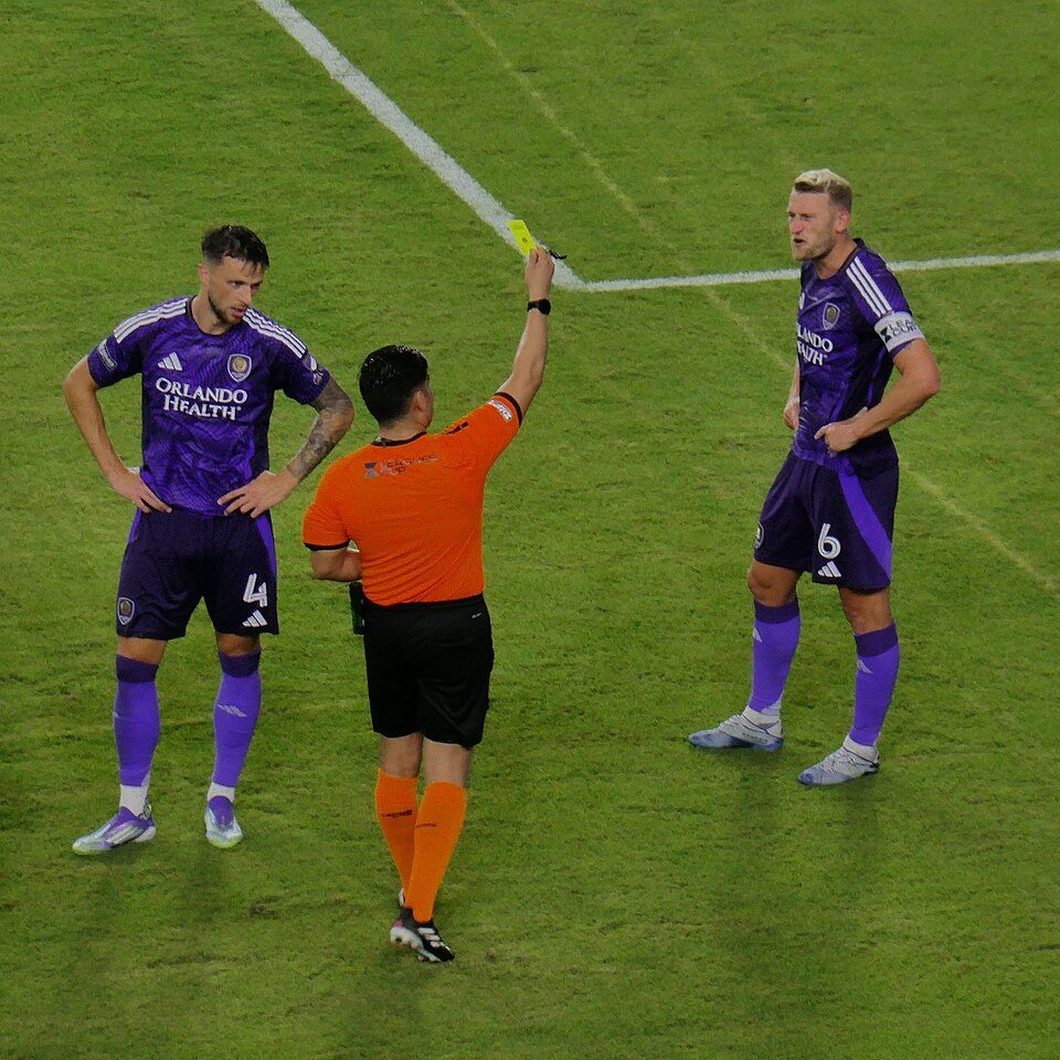 Árbitro mostrando tarjeta amarilla en partido de fútbol